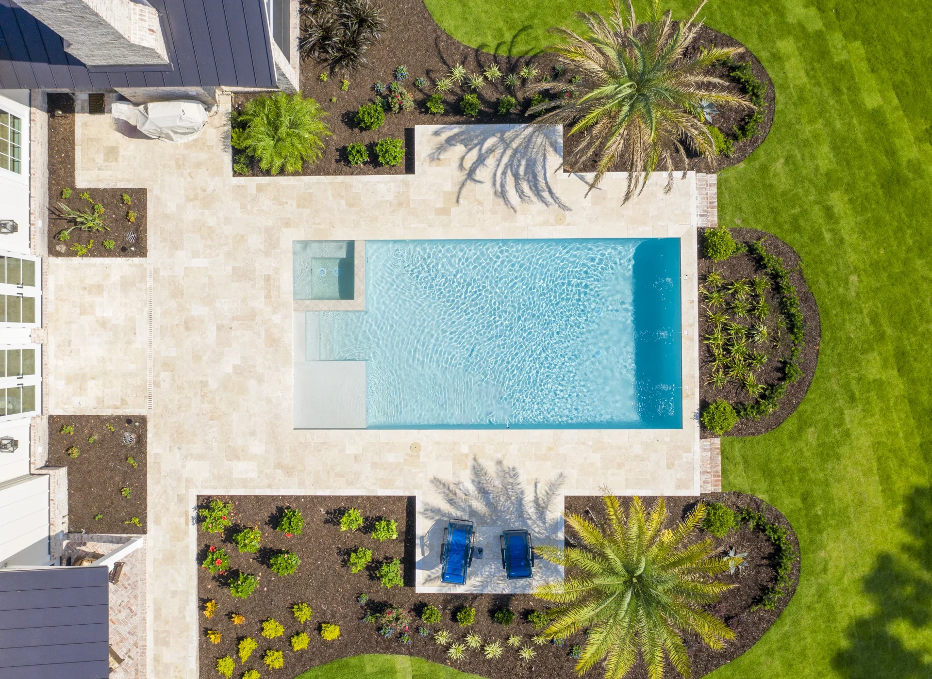 An overhead view of a pool, terrace, and planting beds