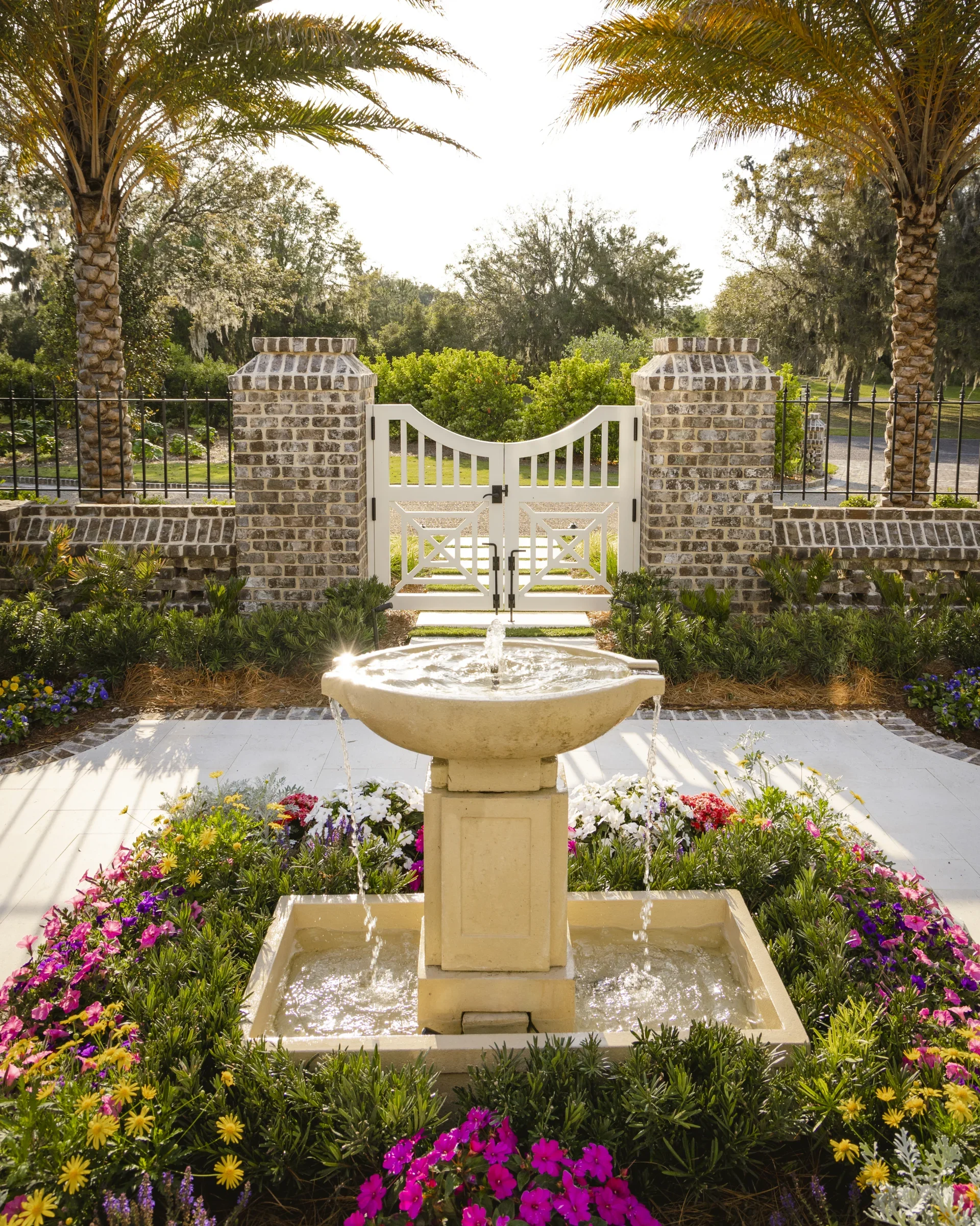 A garden fountain framed by planting and a white garden gate