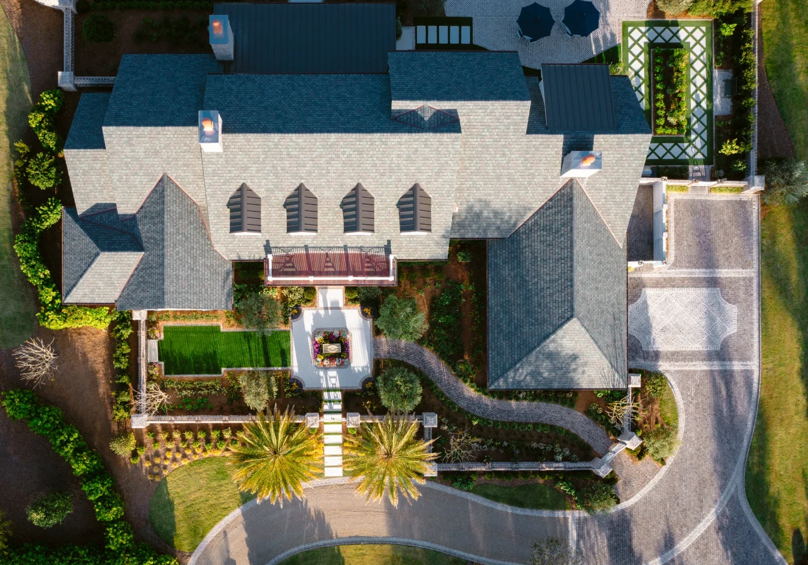 Aerial view of a coastal home with a circular landscaped driveway