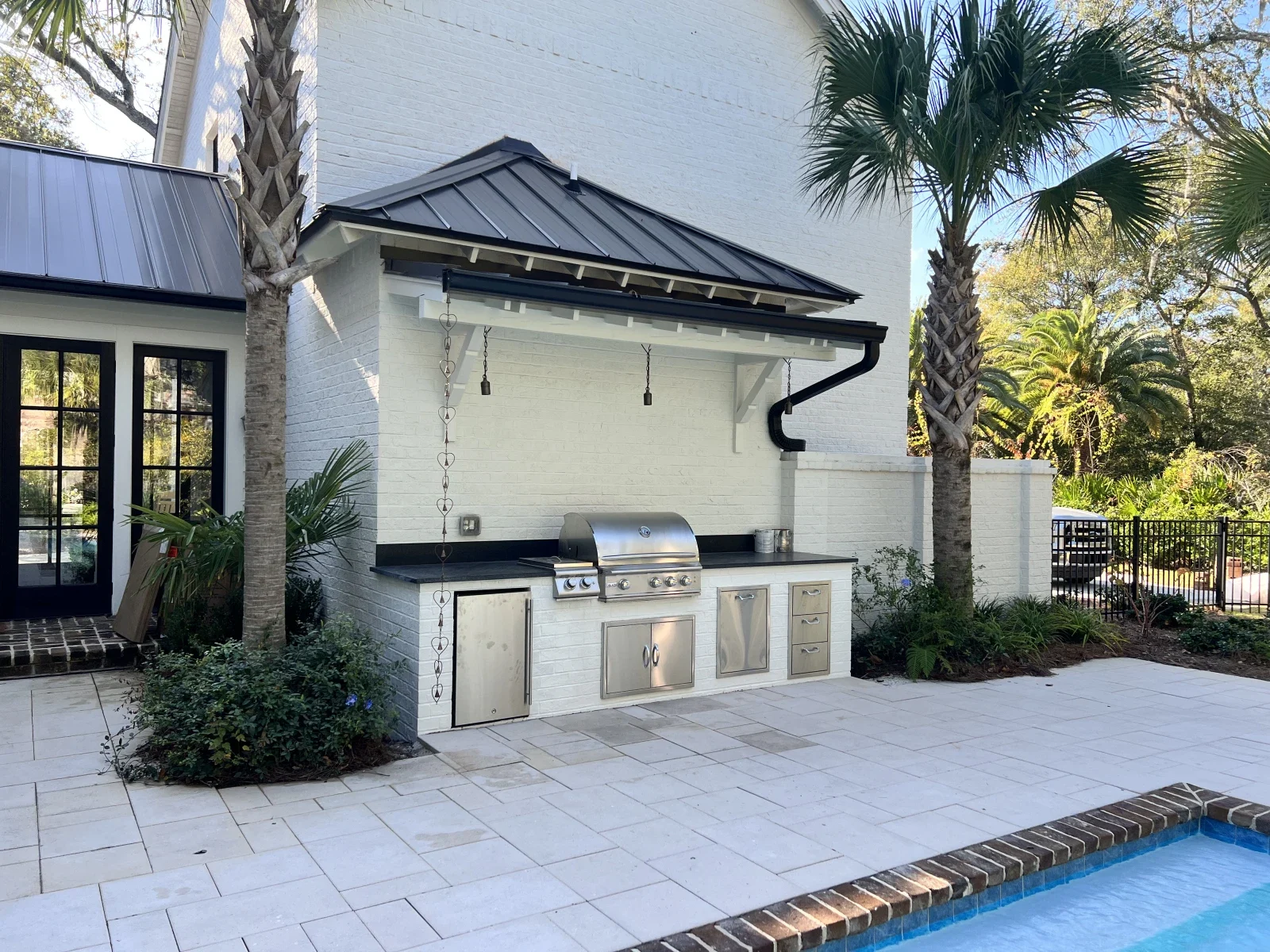 Outdoor grill and kitchen built into a covered white garden structure